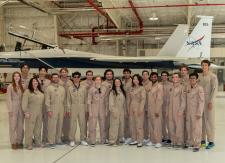 A group of NASA interns posing in an airplane hanger in front of a plane